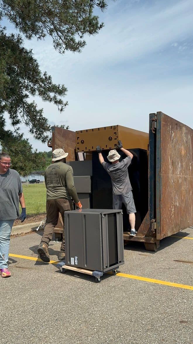 Crew loading metal office cabinets into a container during a commercial cleanout