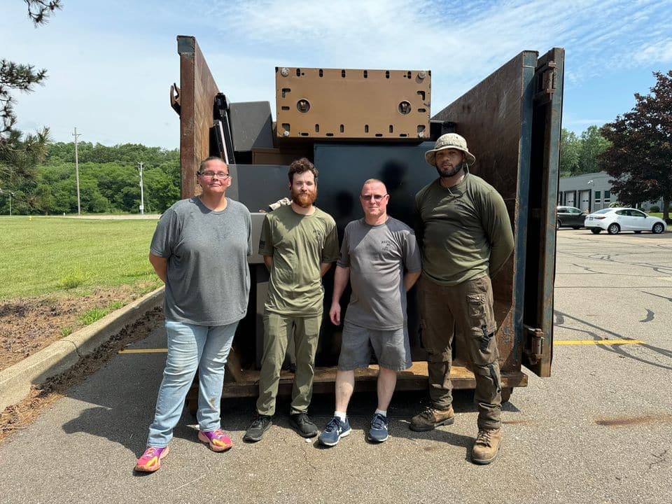 Four Marshall Hauling crew members standing in front of a loaded container after a commercial job