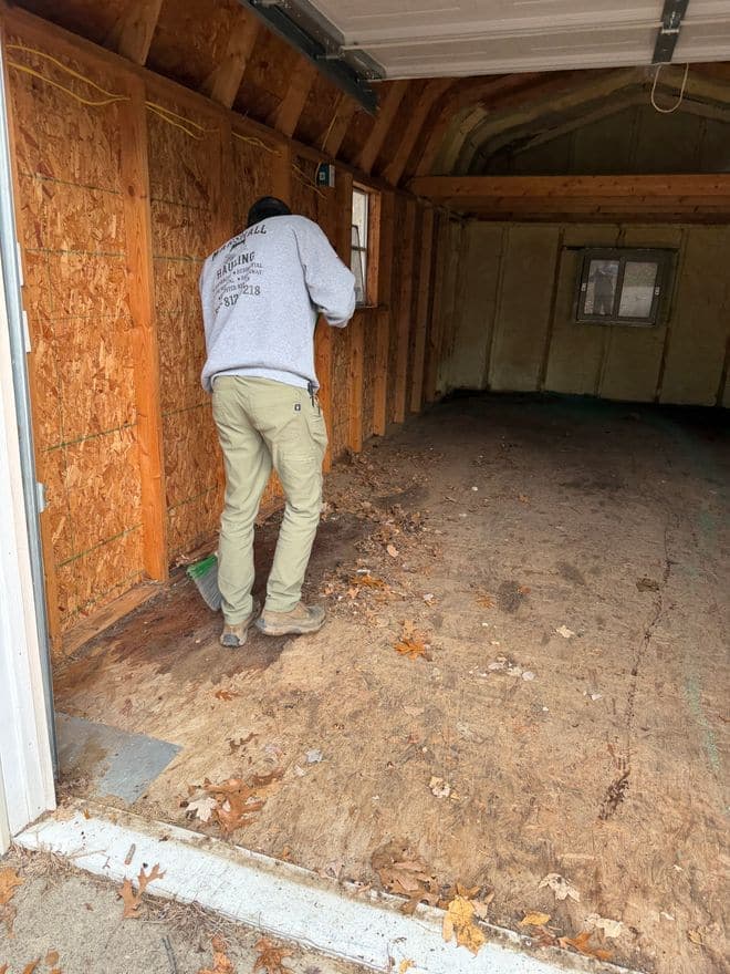 A crew member sweeping out an emptied garage, broom in hand